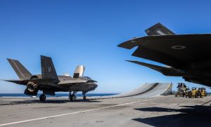 F-35B Lightning II fighters from the U.S. Marine Corps operated from the Royal Navy aircraft carrier HMS Prince of Wales (R09) on Tuesday in preparation for the multinational Exercise Talisman Sabre. The aircraft, from Marine Fighter Attack Squadron 242 (VMFA-242) “Bats,” were seen conducting refuelling and launch preparations aboard the U.K. flagship.